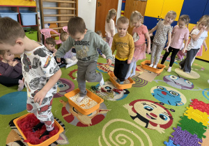 Dzieci po kolei pokonują ścieżkę sensoryczną.