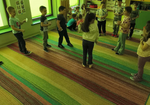 Dzieci, które mają obrazek owocu/warzywa wskazanego przez nauczycielkę ustawiają się przy właściwej ilustracji.