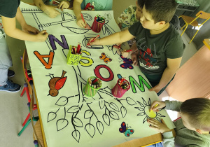 Starsi chłopcy kolorują elementy wybranymi przez siebie kredkami.