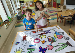 Młodsi chłopcy wraz ze starszymi koleżankami wypełniają elementy przygotowanymi kuleczkami z bibuły.