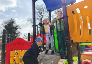 Dzieci na kolorowej konstrukcji na placu zabaw.