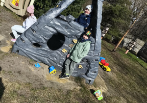 Chłopcy wspinają się na konstrukcję na ogrodzie przedszkolnym.