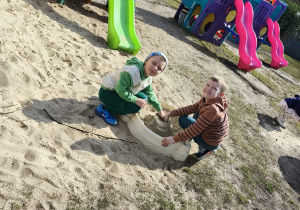 Chłopcy konstruują budowle z piasku na przedszkolnym placu zabaw.