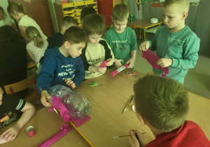 Chłopcy przy połączonych stołach tworzą Eko-skarbonkę "świnkę", która jest świetnym sposobem na budowanie dobrych i odpowiedzialnych nawyków ekologicznych.