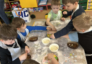Kilkoro dzieci z grupy "Motylków" dekoruje swoją, czekoladową pisankę przy użyciu kolorowych, jadalnych ozdób.