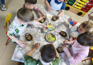 "Pszczółki" przy stole tworzą swoje, czekoladowe pisanki.