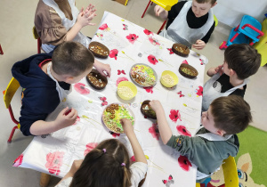 "Pszczółki" przy stole tworzą swoje, czekoladowe pisanki.