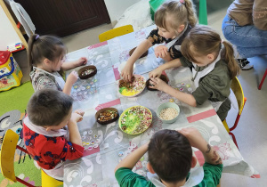 "Pszczółki" przy stole tworzą swoje, czekoladowe pisanki.