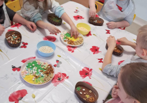 Dzieci z grupy III podczas zdobienia czekoladowych pisanek przy użyciu kolorowych, jadalnych ozdób.