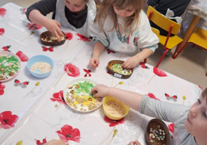 Kilkoro dzieci z grupy "Żabek" dekoruje swoją, czekoladową pisankę.