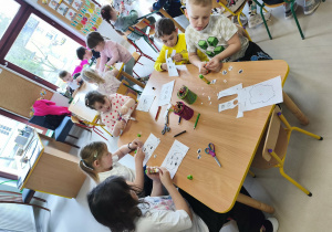 Kilkoro dzieci przy stole podczas pracy plastyczno-technicznej.