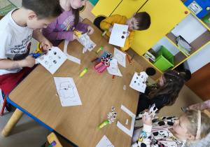 Kilkoro dzieci przy stole podczas pracy plastyczno-technicznej.