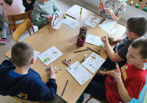 Kilkoro dzieci przy stole podczas pracy plastyczno-technicznej.