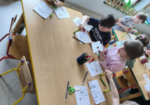 Kilkoro dzieci przy stole podczas pracy plastyczno-technicznej.