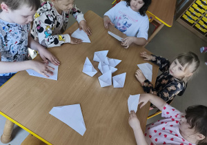 Chętne dzieci, przy wsparciu nauczycielki tworzą swoje, papierowe łódki.