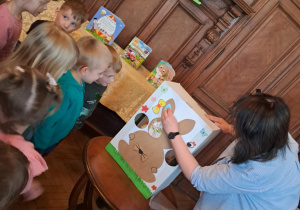 Bibliotekarka dekoruje zajączka rozmaitymi ozdobami.