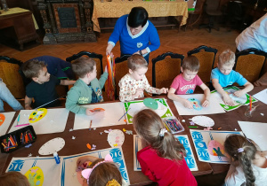 Ciocia Agnieszka z biblioteki rozdaje "Motylkom" kolorowe wstążki.