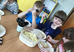 Chętne dzieci nakładają sobie na talerzyk kromkę chleba tostowego oraz przygotowaną pastę jajeczną.