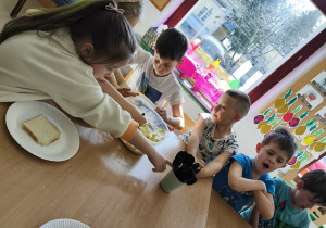 Chętne dzieci nakładają sobie na talerzyk kromkę chleba tostowego oraz przygotowaną pastę jajeczną.