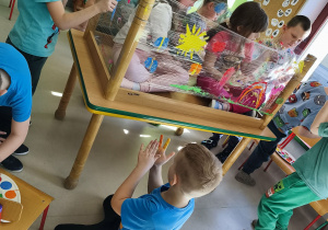 Pierwszy zespół maluje wiosnę według własnego pomysłu korzystając z folii stretch, farb w wiosennych kolorach i swoich paluszków.