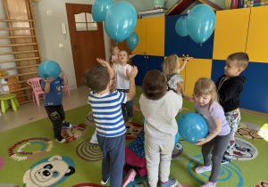 Zabawy ruchowe z niebieskimi balonami wśród dzieci z grupy II.