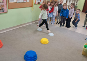 "Żabki" przechodzą boso po ułożonej ścieżce sensorycznej.