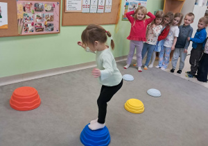 "Żabki" przechodzą boso po ułożonej ścieżce sensorycznej.