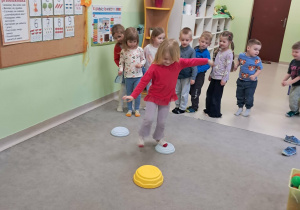 "Żabki" przechodzą boso po ułożonej ścieżce sensorycznej.