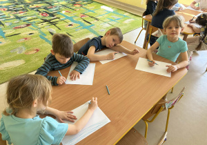 Kilkoro dzieci z grupy "Motylków" w ramach zajęć dotyczących autyzmu, tworzy pracę plastyczną.