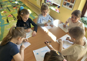 Kilkoro dzieci z grupy "Motylków" w ramach zajęć dotyczących autyzmu, tworzy pracę plastyczną.