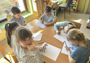 Kilkoro dzieci z grupy "Motylków" w ramach zajęć dotyczących autyzmu, tworzy pracę plastyczną.