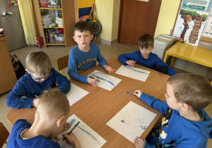 Kilkoro dzieci z grupy "Motylków" w ramach zajęć dotyczących autyzmu, tworzy pracę plastyczną.