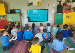 "Pszczółki" na zajęciach porannych oglądają prezentację nt. autyzmu na ekranie multimedialnym.