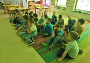 Dzieci z grupy "Pszczółek" siedzą na dywanie i słuchają ważnych informacji nt. autyzmu.