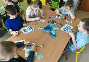 "Pszczółki" formują kuleczki z niebieskiej bibuły i wyklejają nimi wybrane przez siebie litery.