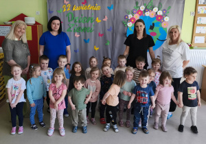 Grupowe zdjęcie dzieci wraz z paniami z grupy "Jeżyków" na tle przygotowanej wcześniej dekoracji tematycznej.