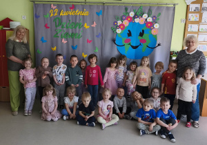 Grupowe zdjęcie dzieci wraz z paniami z grupy "Wiewiórek" na tle przygotowanej wcześniej dekoracji tematycznej.