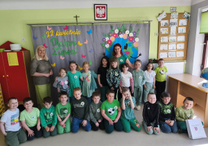 Grupowe zdjęcie dzieci wraz z paniami z grupy "Pszczółek" na tle przygotowanej wcześniej dekoracji tematycznej.