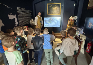 Chłopcy zwiedzają Muzeum Pałacu Saskiego w Kutnie, słuchając opowieści przewodnika.