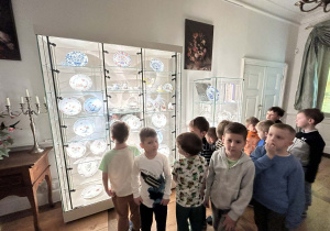 Chłopcy zwiedzają Muzeum Pałacu Saskiego w Kutnie, słuchając opowieści przewodnika.