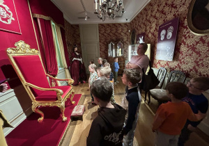 Chłopcy zwiedzają Muzeum Pałacu Saskiego w Kutnie, słuchając opowieści przewodnika.