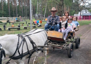 Kilkoro dzieci podczas przejażdżki bryczką zaprzegniętą w kucyka.