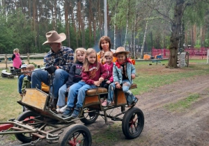 Kilkoro dzieci podczas przejażdżki bryczką zaprzegniętą w kucyka.