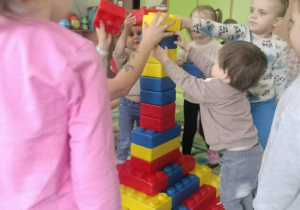 Dzieci budują z klocków piramidę.