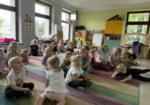 Młodsze dzieci oglądają film edukacyjny nt. bezpieczeństwa podczas przejazdu przez tory kolejowe.