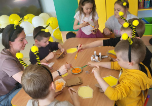 Kilkoro dzieci wraz z Rodzicami tworzy swoje plasterki miodu z wykorzystaniem szablonu, folii bombelkowej, farby i pędzelków.