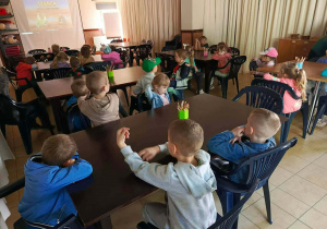 Dzieci z grupy IV oglądają prezentację multimedialną na temat dinozaurów.