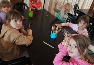 Dzieci z grupy IV zdobią drewniane figurki dinozaurów.