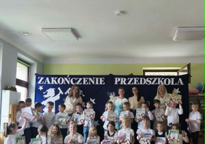 Pamiątkowe zdjęcie dzieci z grupy V na tle przygotowanej wcześniej dekoracji tematycznej.