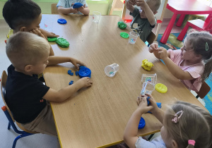 Zabawa kolorową ciastoliną przy stoliku.